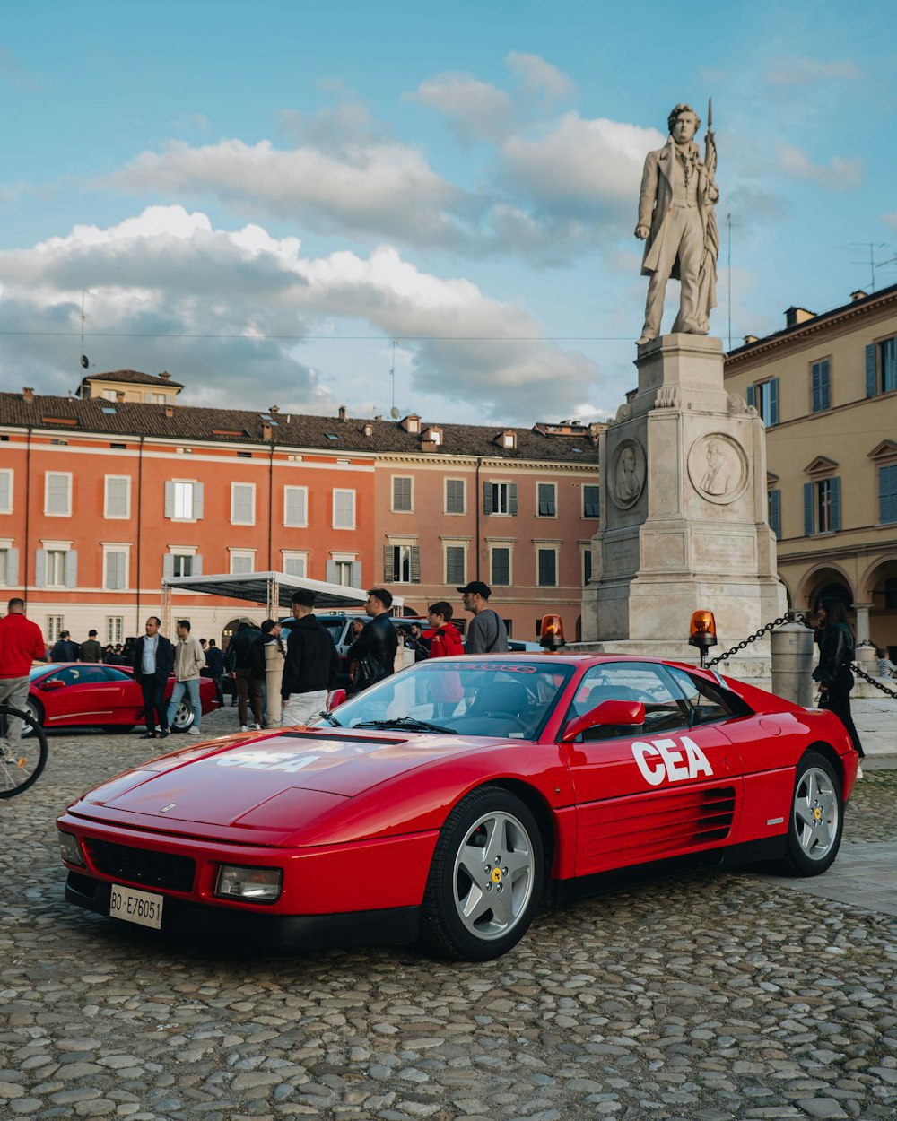 a red sports car parked in front of a statue