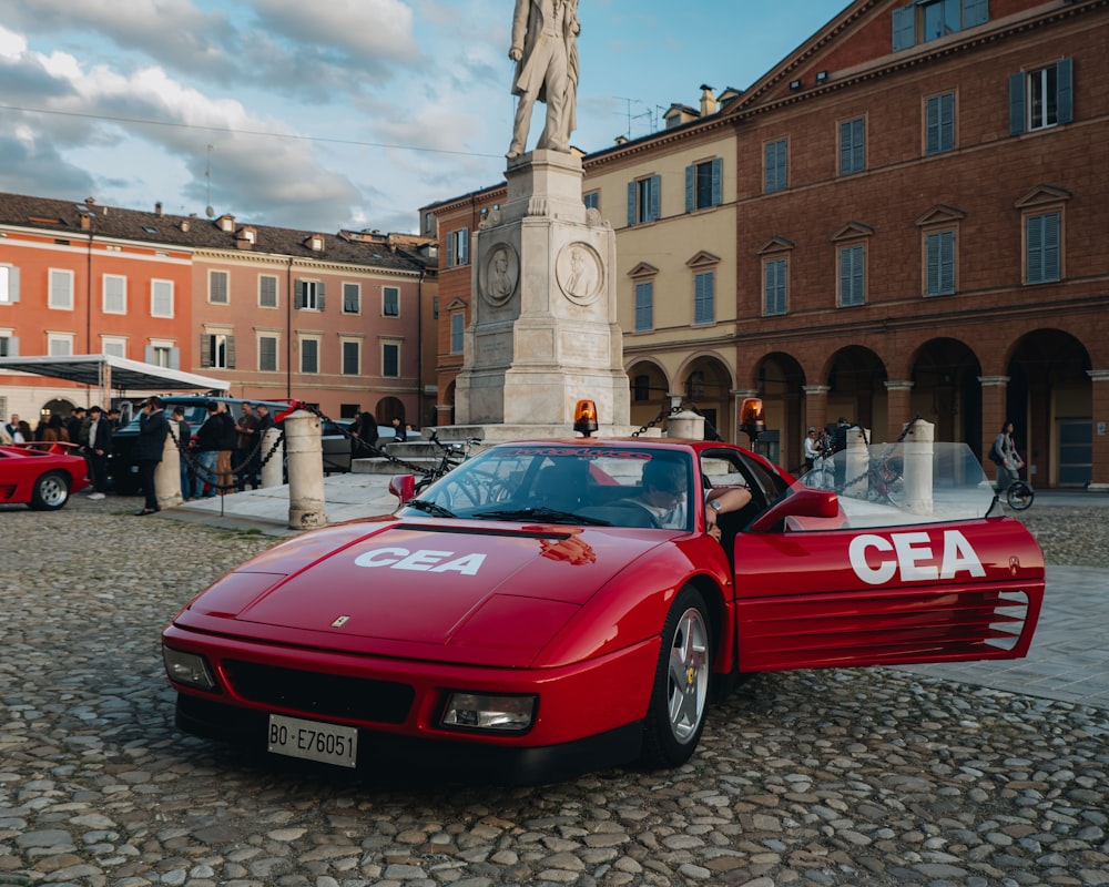 a red sports car parked in front of a statue