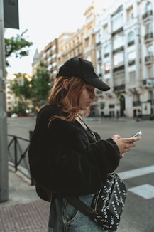 a woman standing on a street corner looking at her cell phone