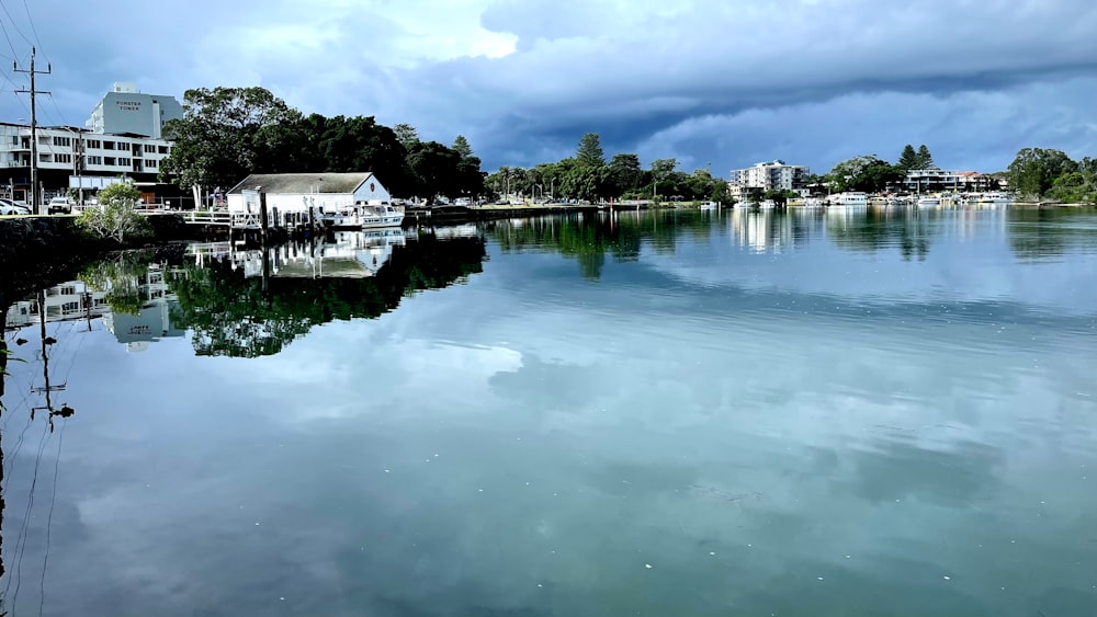 a body of water with houses and clouds in the background