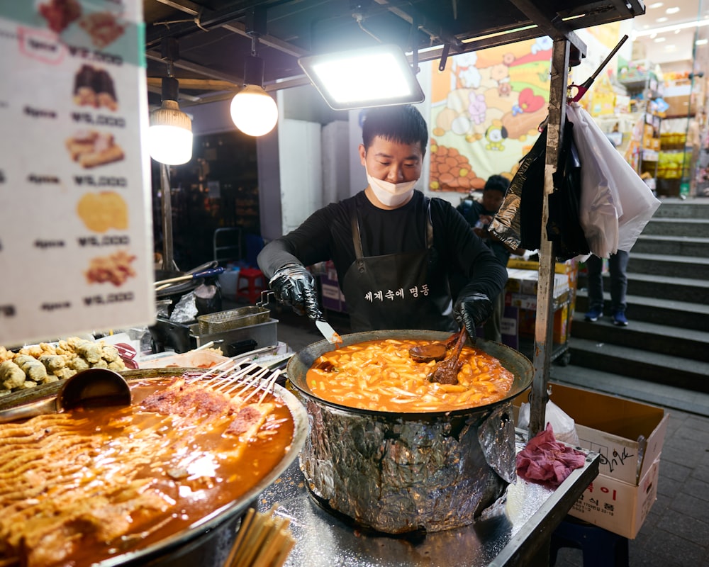 a man wearing a face mask standing in front of a buffet