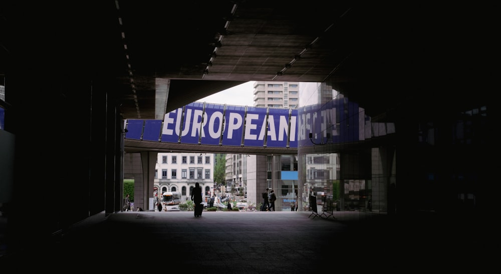 a person walking under a bridge with a european sign above it