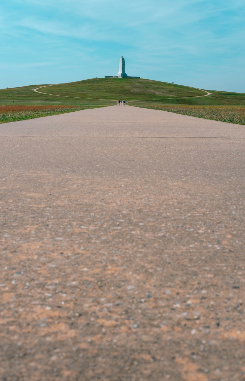 a person walking down a paved road towards a light house