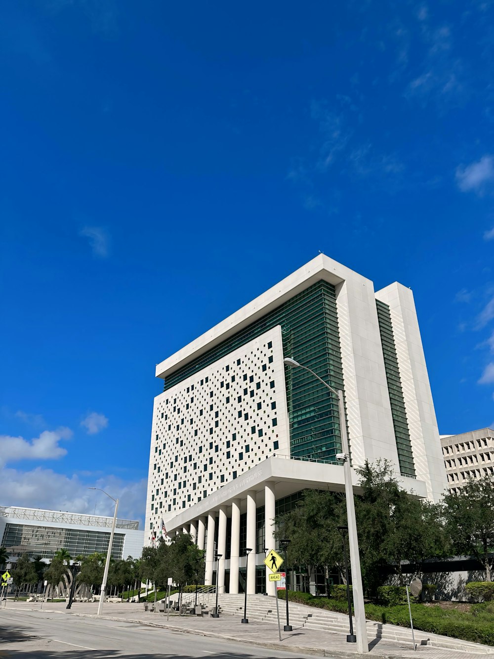 a tall white building sitting next to a lush green park