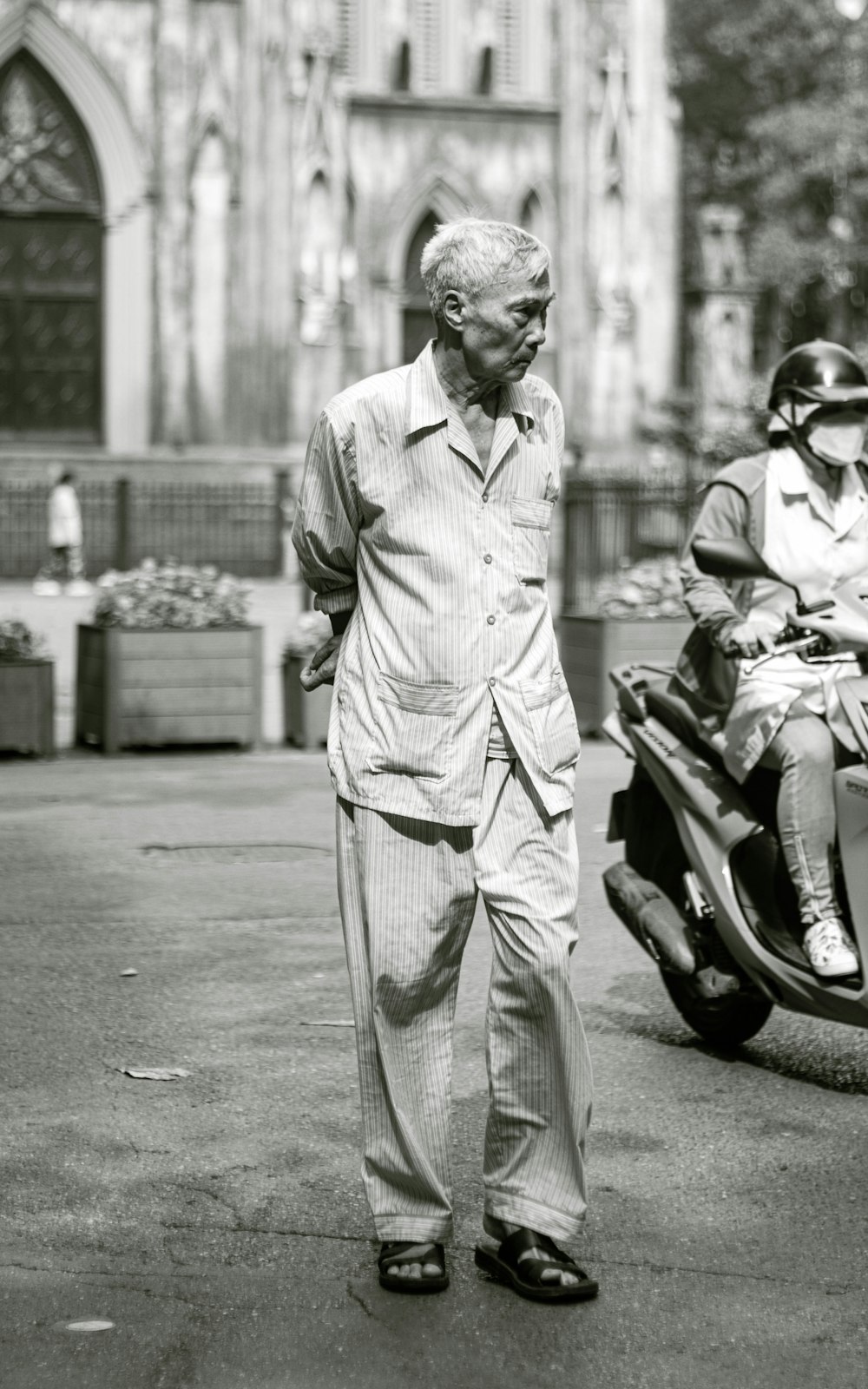 a man walking down a street next to a motorcycle