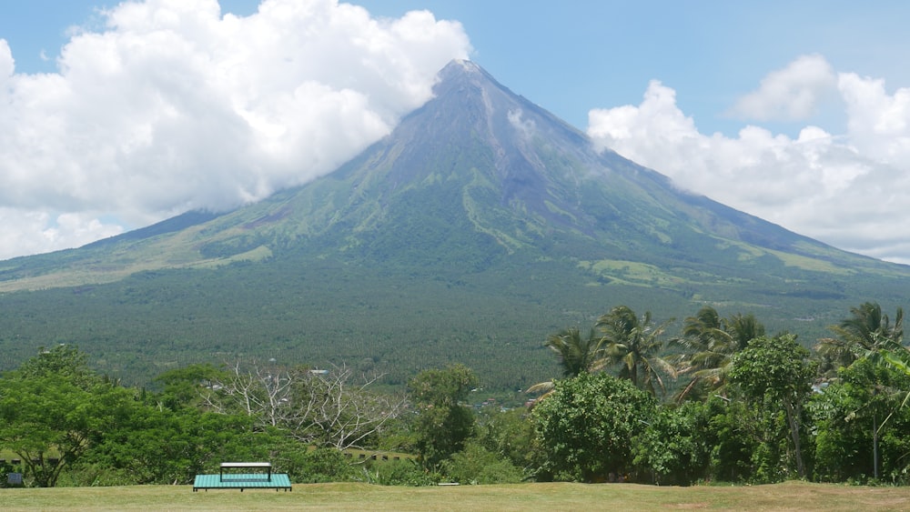 a green bench in front of a large mountain