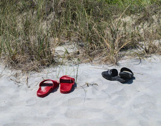 a pair of red shoes sitting on top of a sandy beach