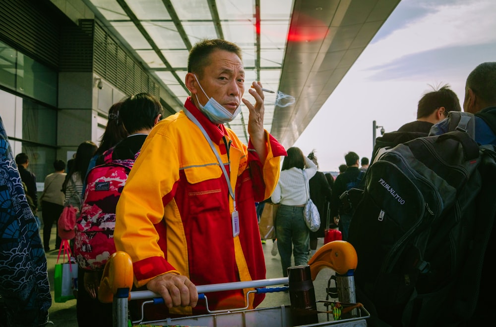 a man in a yellow and red jacket holding a piece of luggage