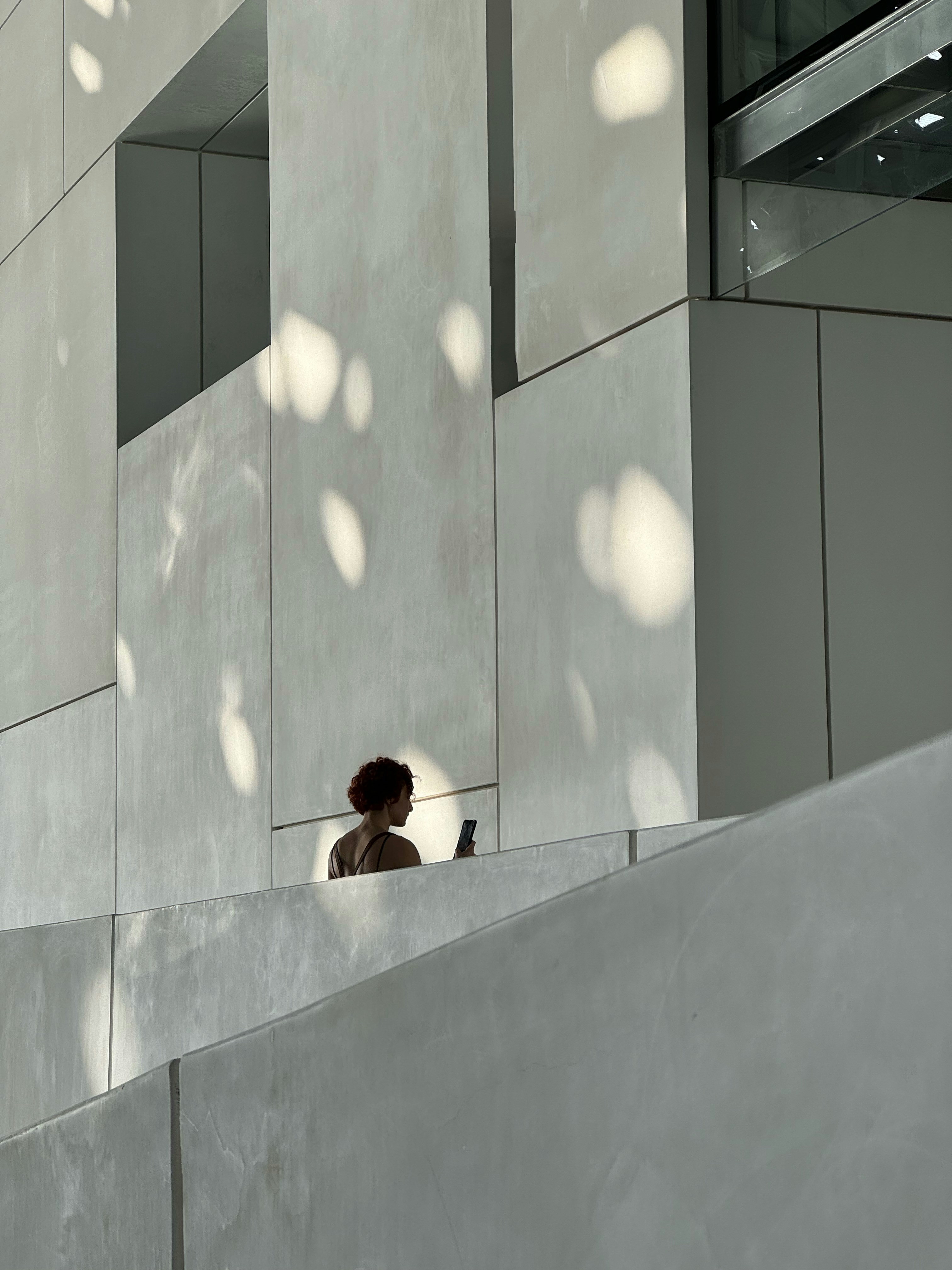 a woman standing on a ledge looking at her cell phone
