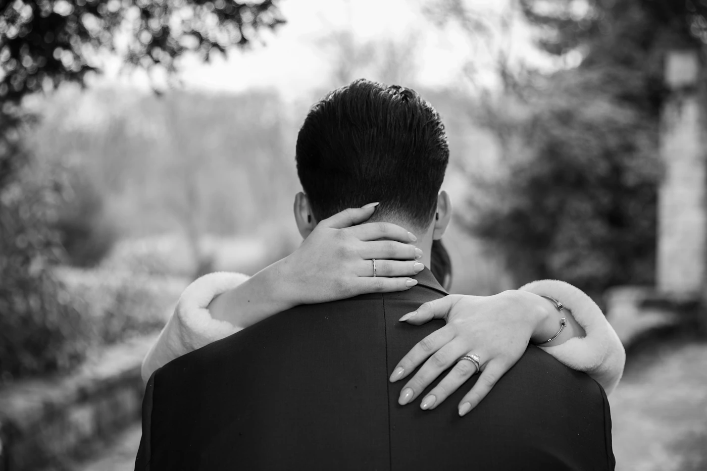 Black and white photograph of a couple in a romantic embrace the man holding the woman close with hands on her back