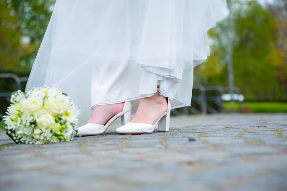 a close up of a bride's shoes and bouquet
