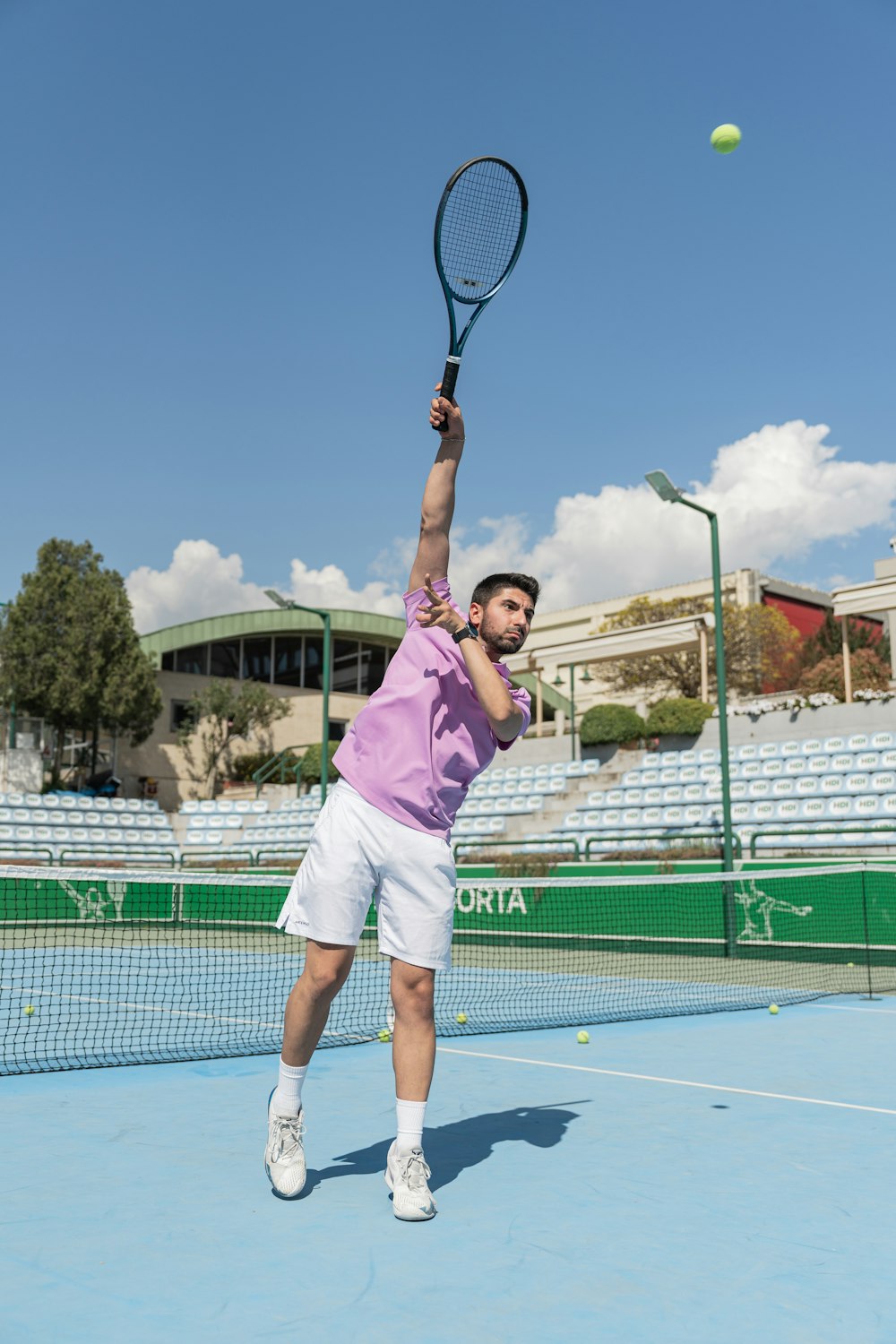 a man in a pink shirt and white shorts playing a game of tennis