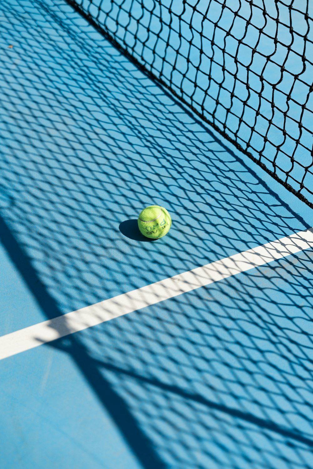 une balle de tennis posée sur un filet de court de tennis