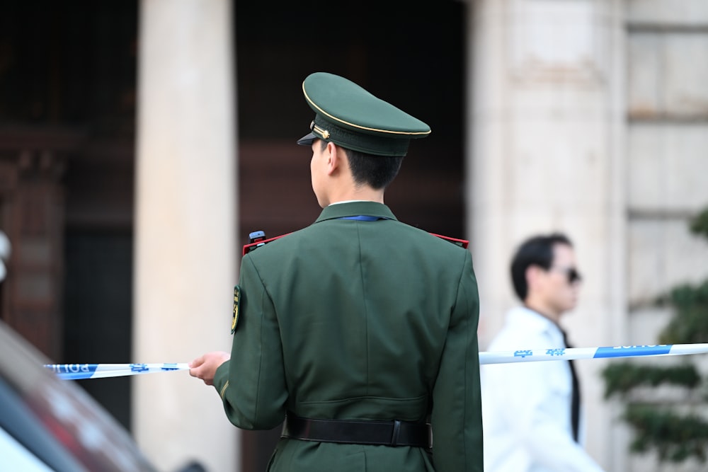 a man in a green uniform standing in front of a building