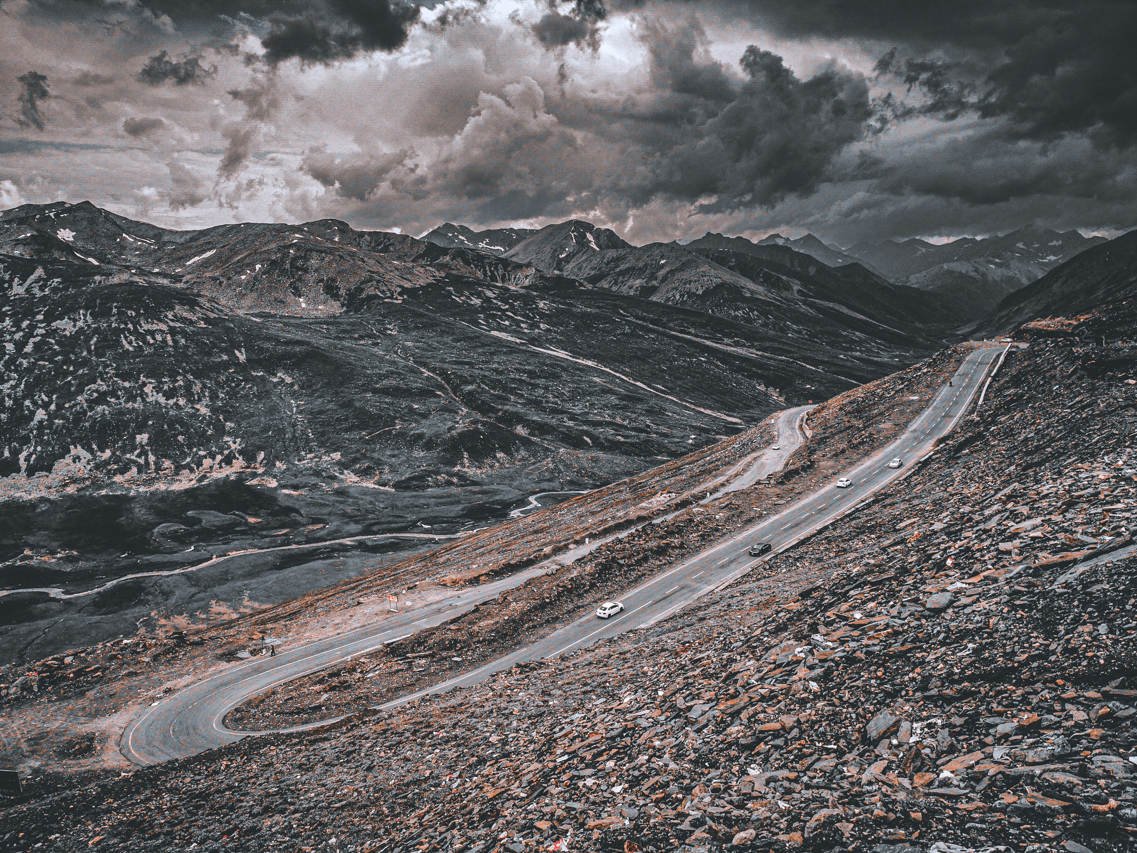 a car driving down a mountain road under a cloudy sky