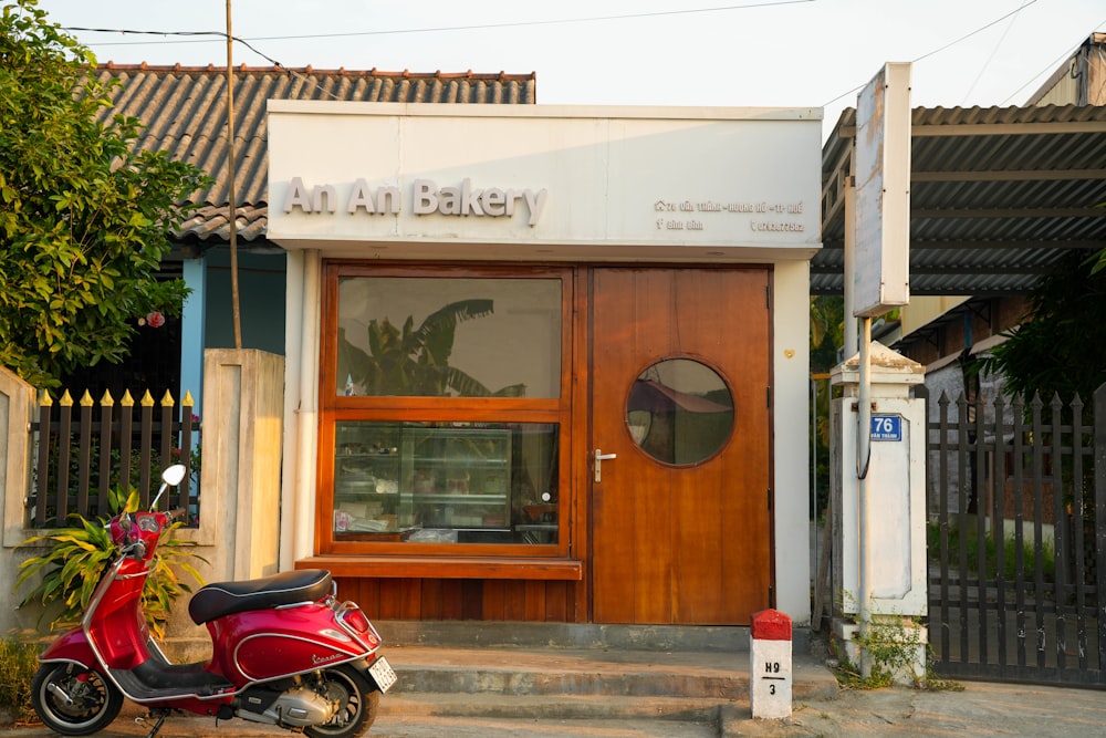 a red scooter parked in front of a bakery
