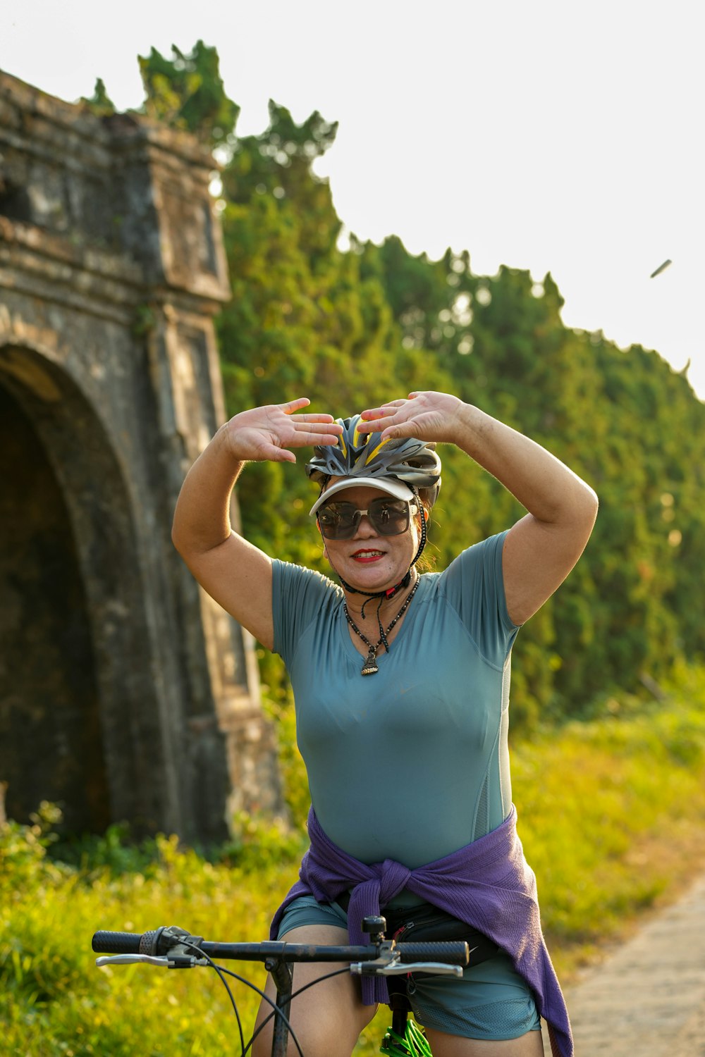 a woman riding a bike down a dirt road