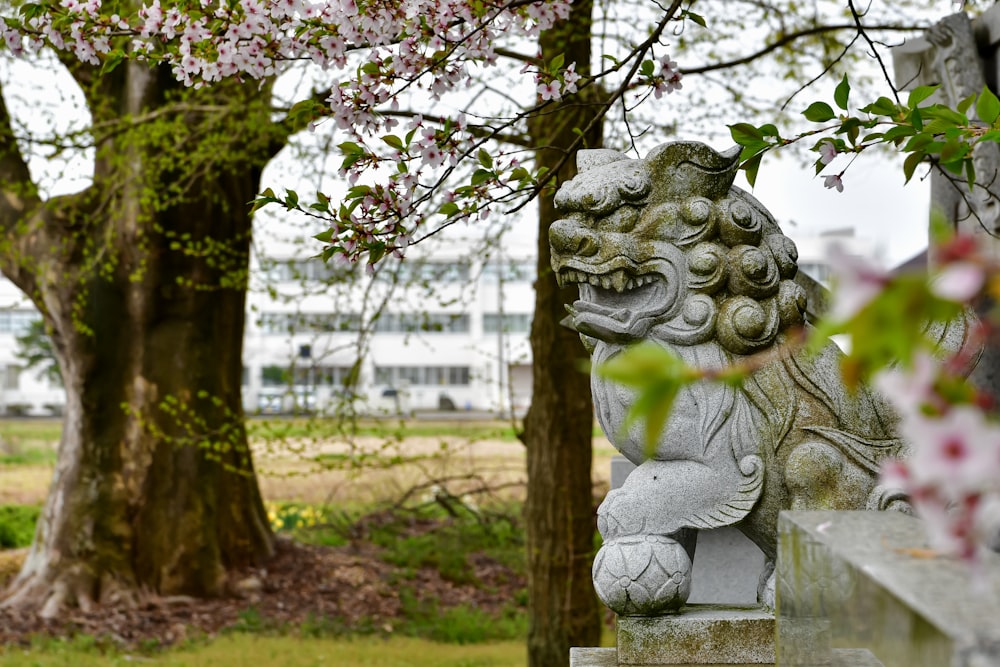 une statue en pierre d’un lion dans un parc