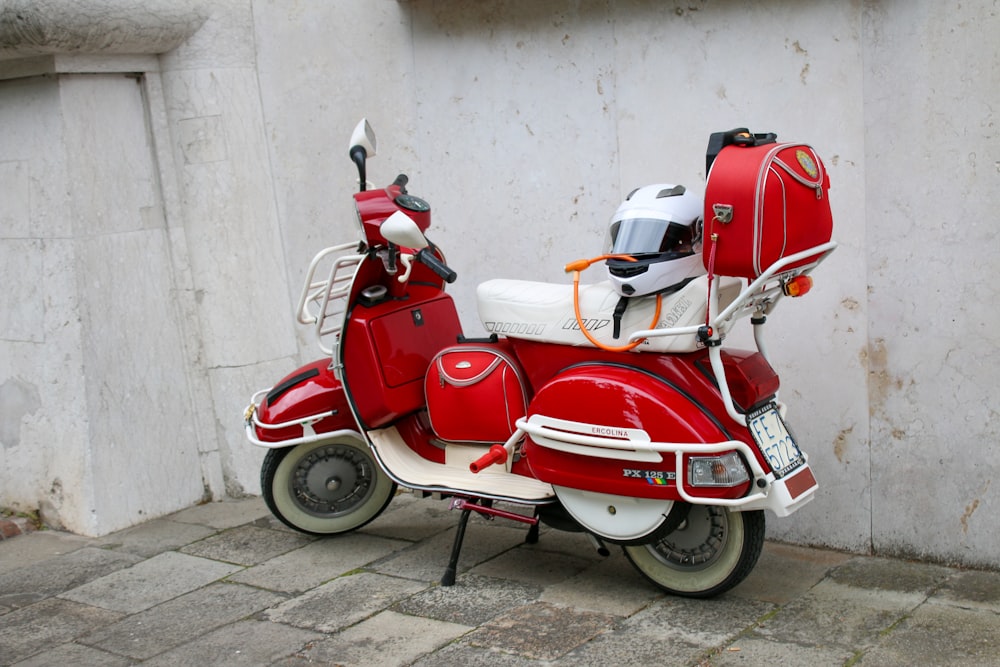 a red scooter parked next to a white wall