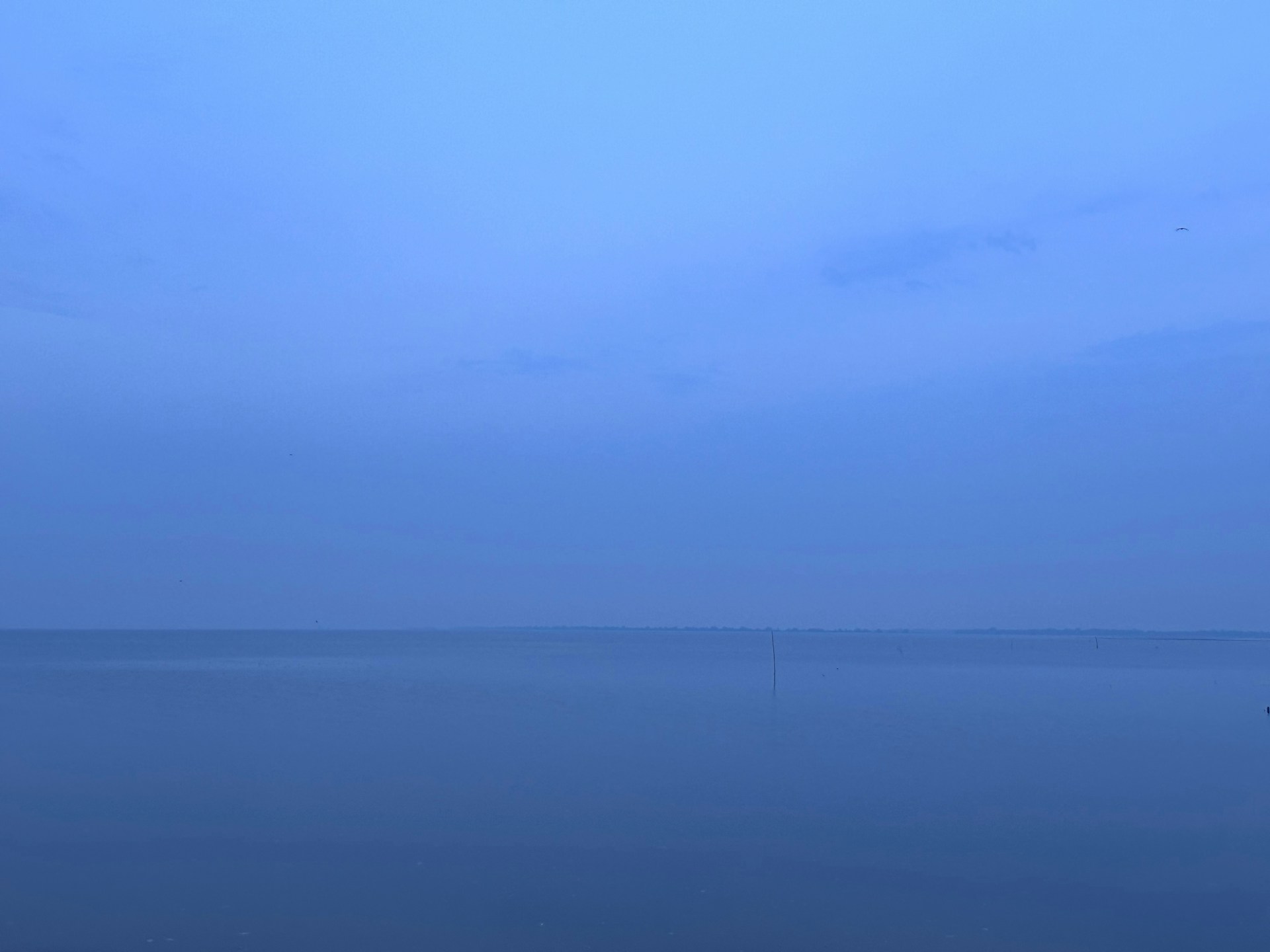 a large body of water sitting under a blue sky
