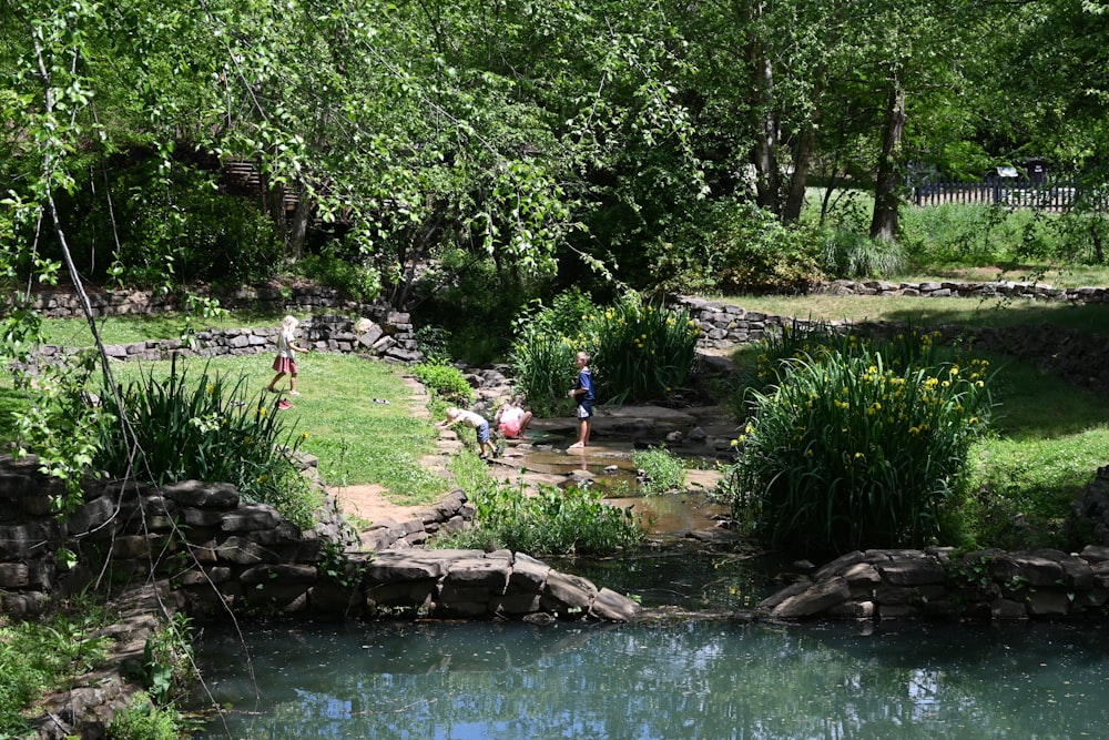 a group of people standing around a pond