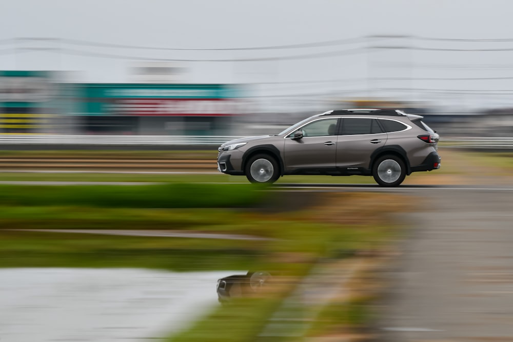 a car driving down a road next to a lush green field