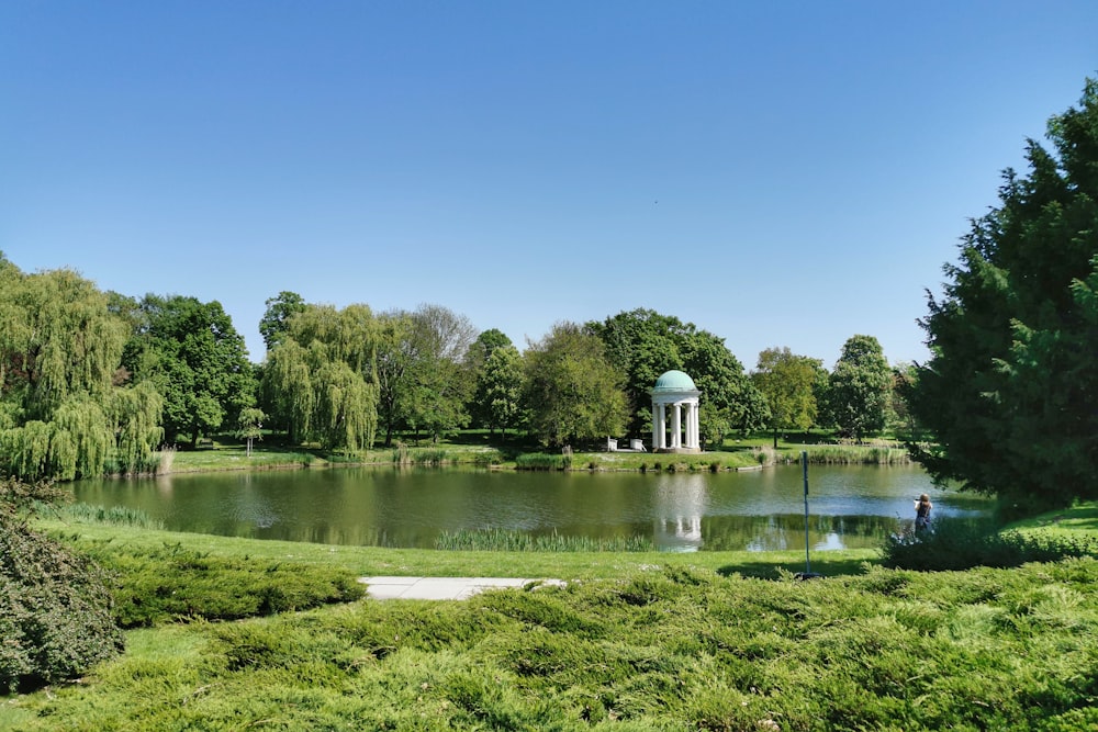 a pond in a park with a gazebo in the background