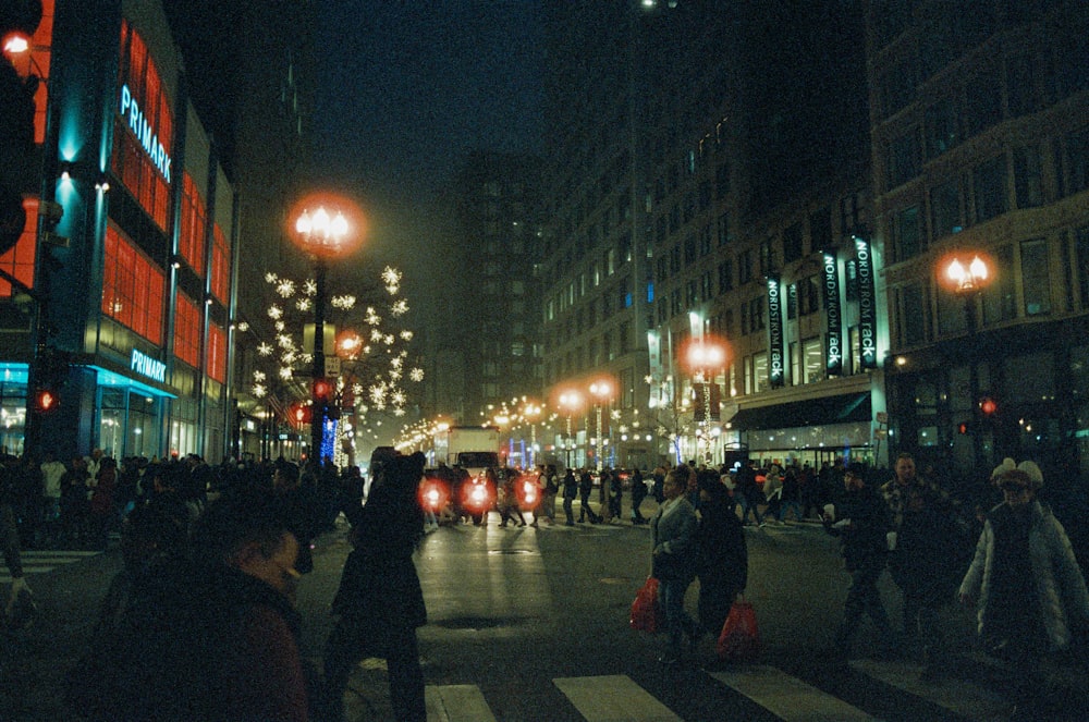 a crowded city street at night with people crossing the street