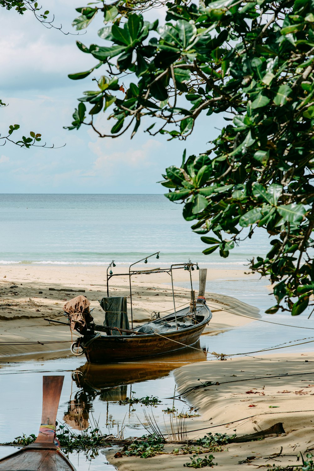 a boat sitting on top of a beach next to the ocean