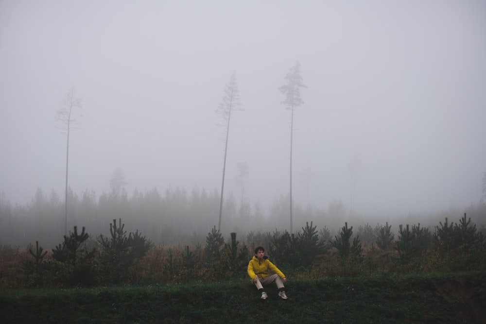 a person sitting on a hill in the fog