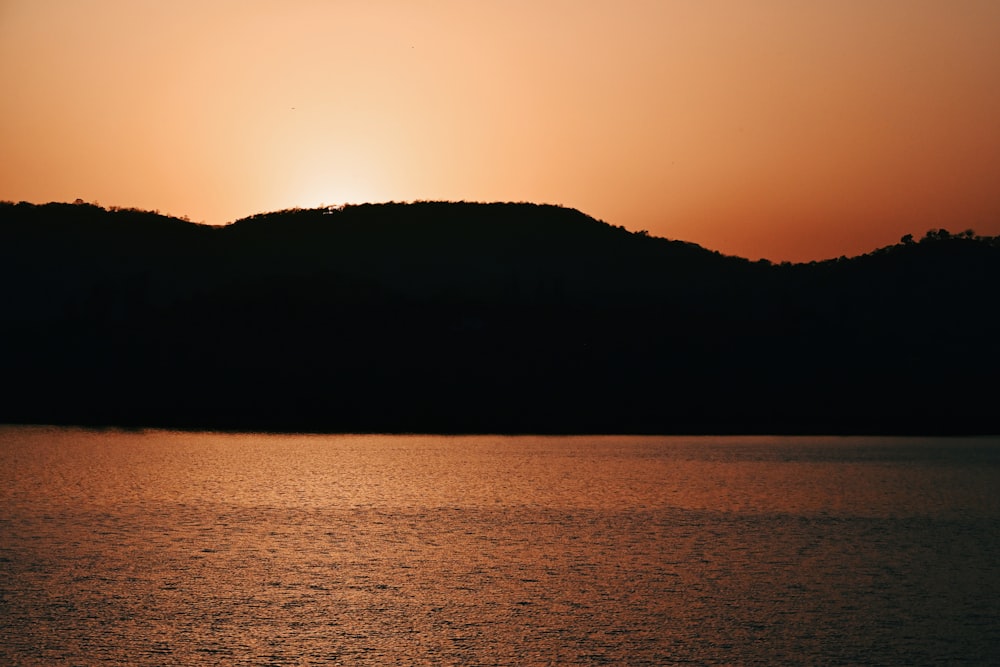 a large body of water with a hill in the background