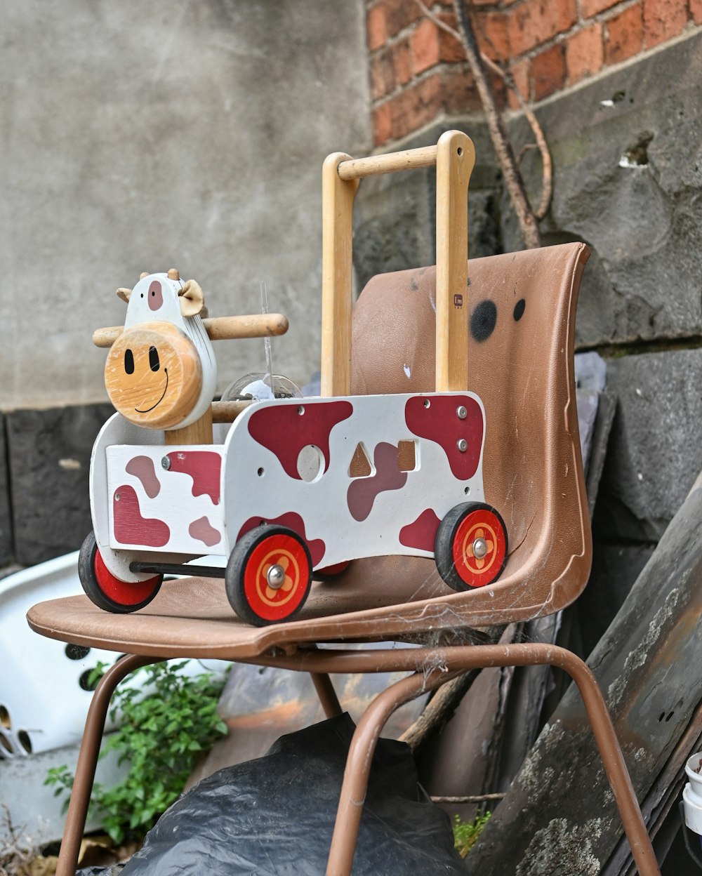 a toy cow sitting on top of a wooden chair