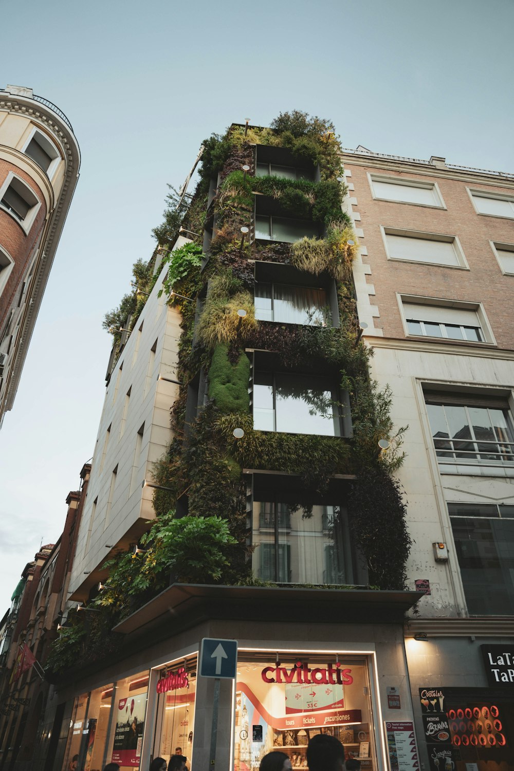 a tall building with plants growing on the side of it
