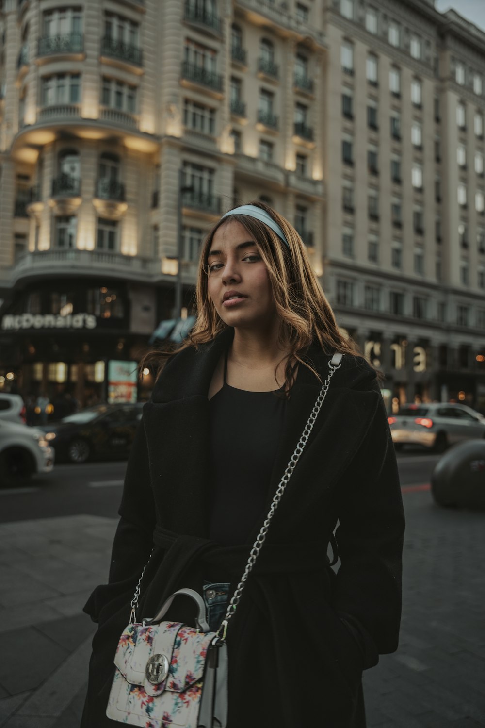 a woman in a black coat is standing on the street