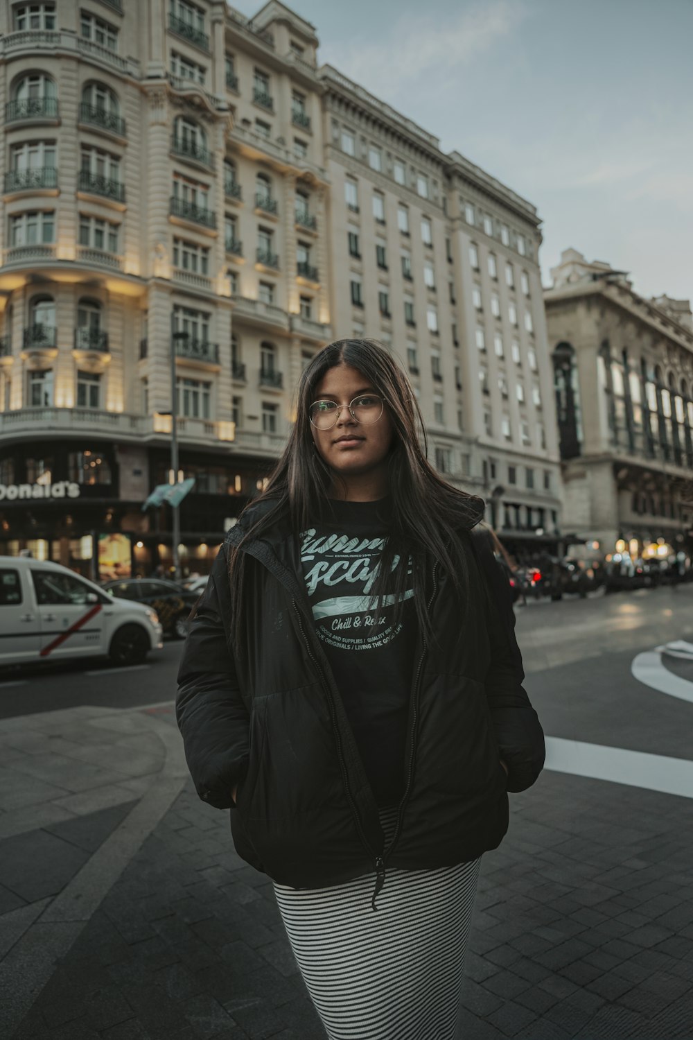 a woman standing on a street corner in front of a building