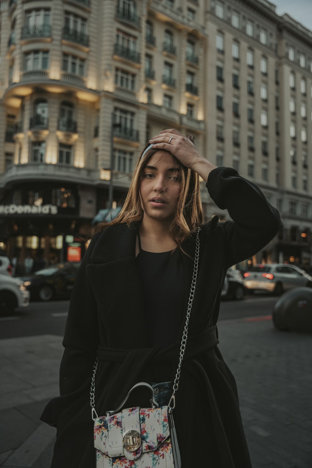 eine Frau, die auf einer Straße steht und eine Handtasche in der Hand hält