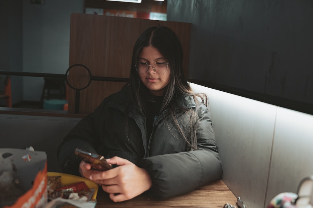 a woman sitting at a table looking at her cell phone