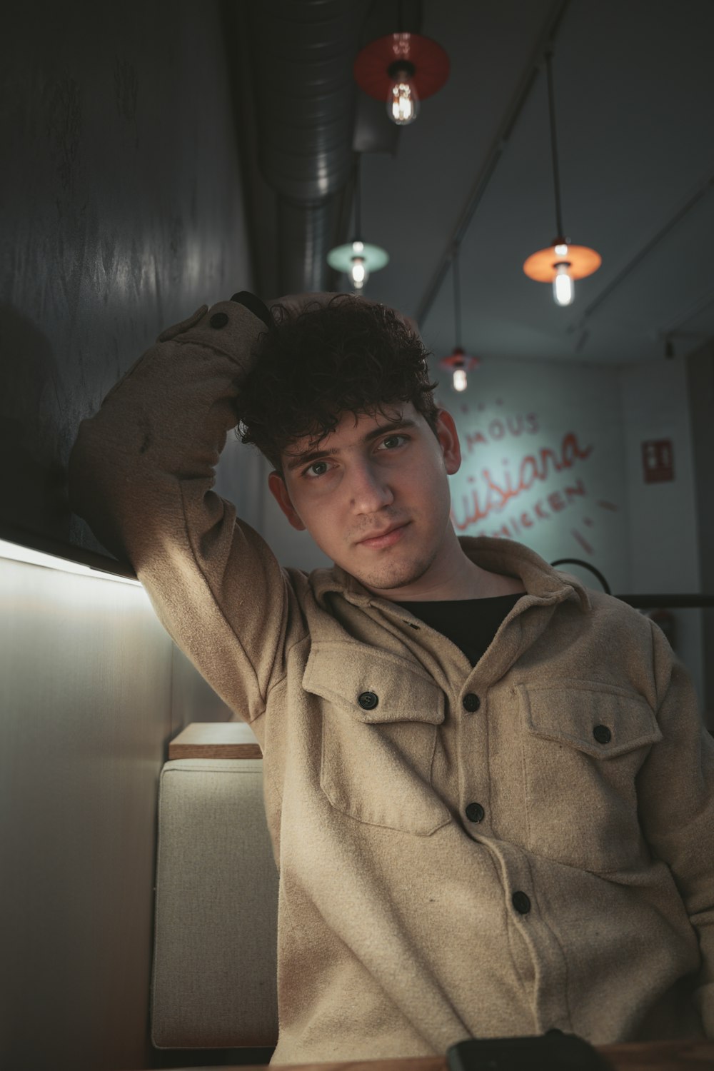 a young man sitting at a table with his hand on his head