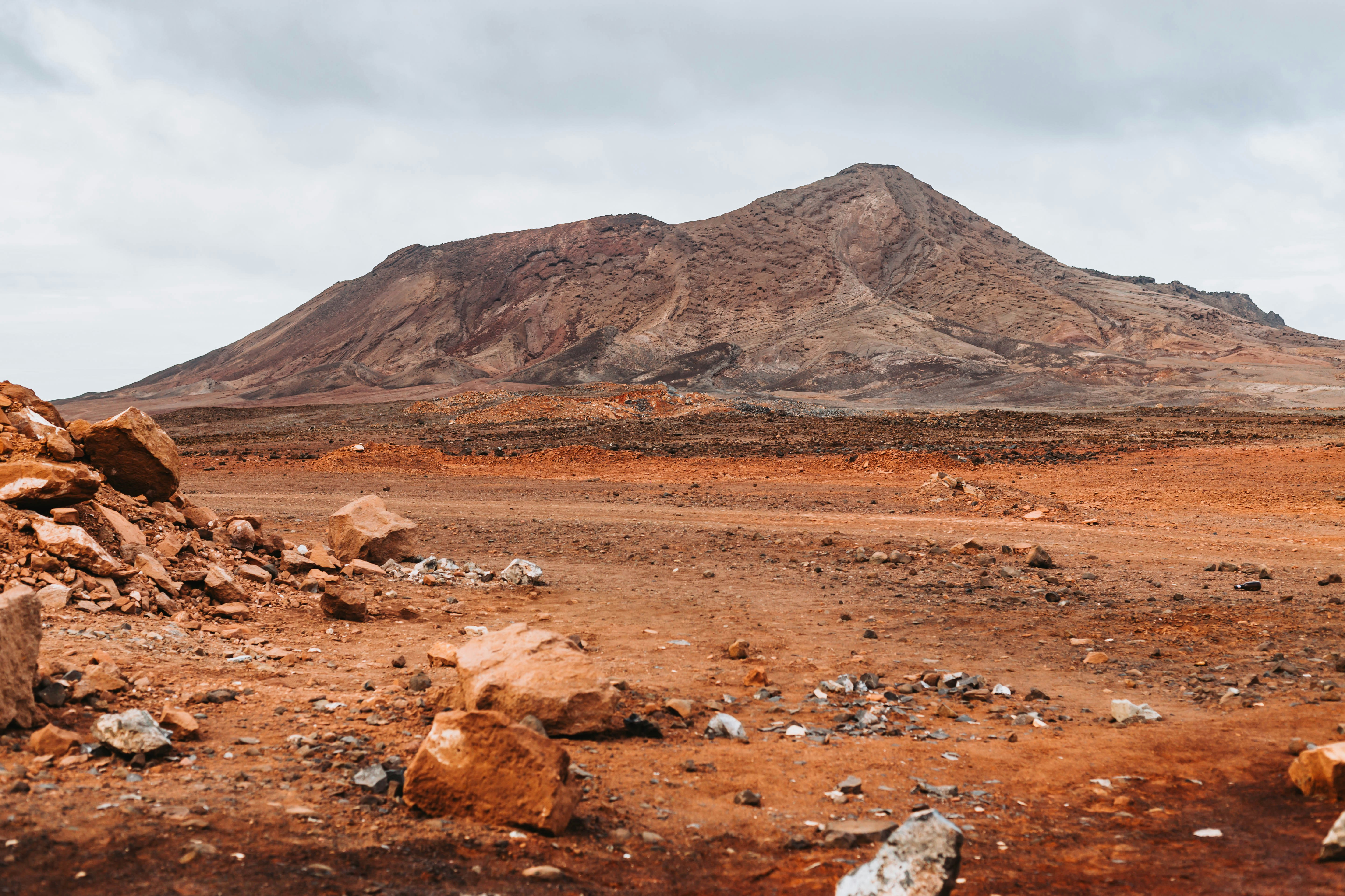 un campo de tierra con rocas y una montaña al fondo
