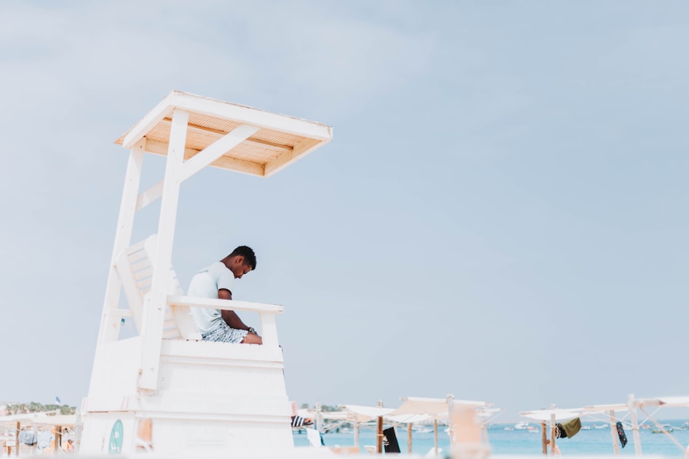 a man sitting on top of a white structure next to the ocean