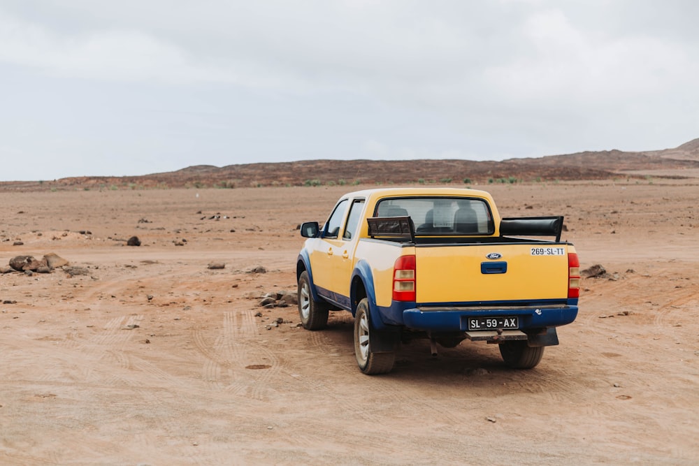 a yellow pick up truck parked in the desert