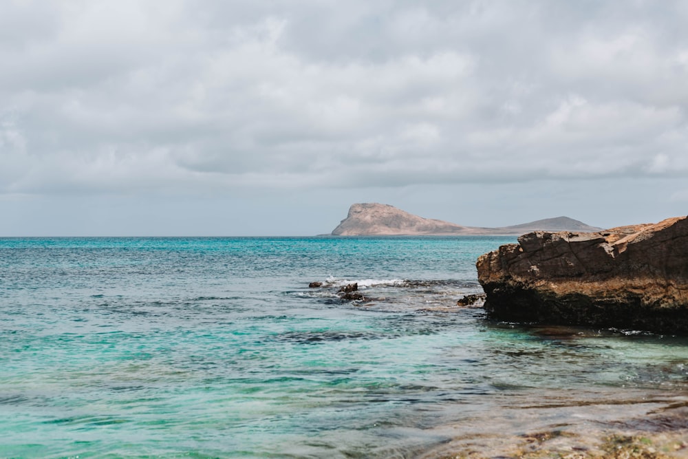 a body of water with rocks and a mountain in the background