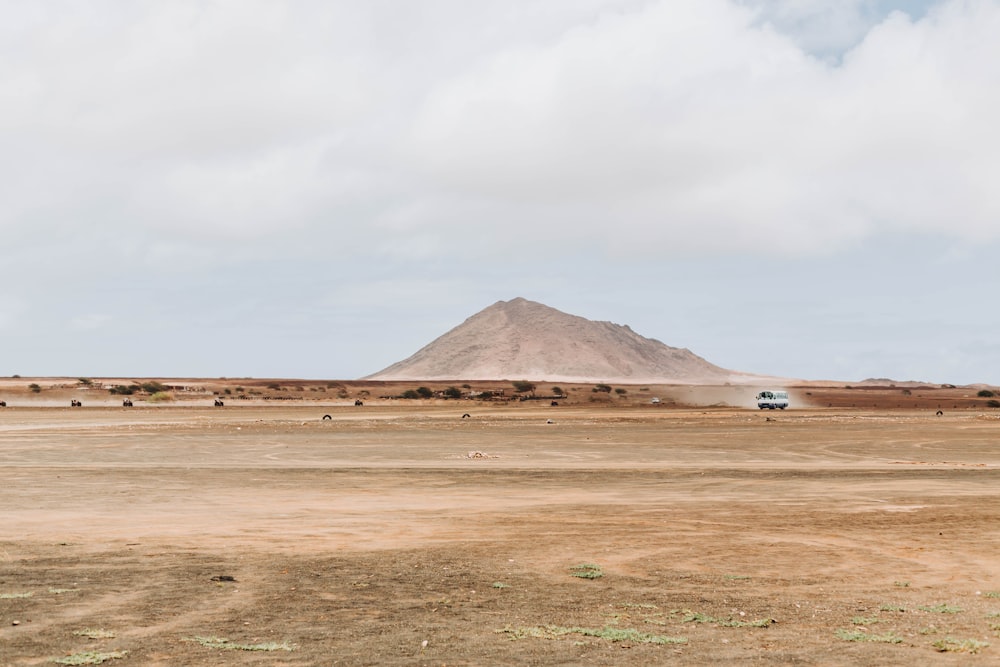 un campo de tierra con una colina al fondo