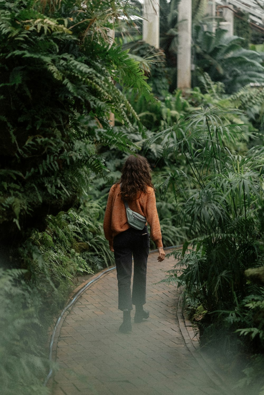 a woman walking down a path through a lush green forest