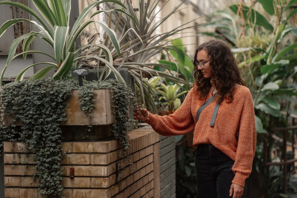 a woman standing next to a brick planter