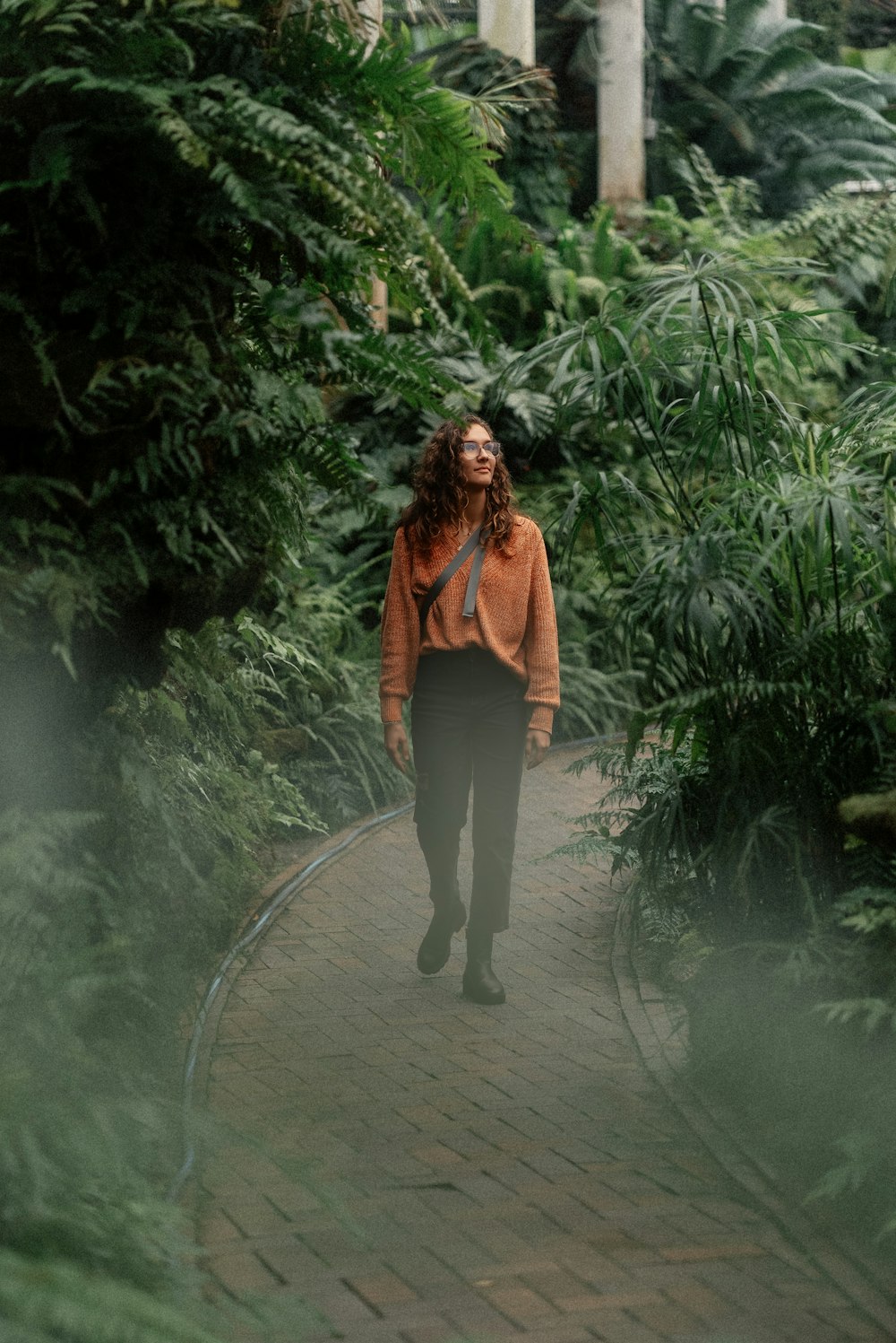 a woman walking down a brick path in a forest