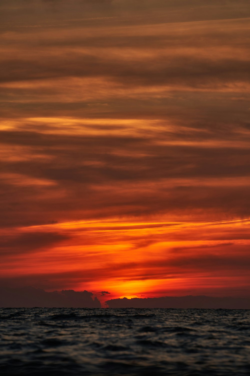 the sun is setting over the ocean with a boat in the distance