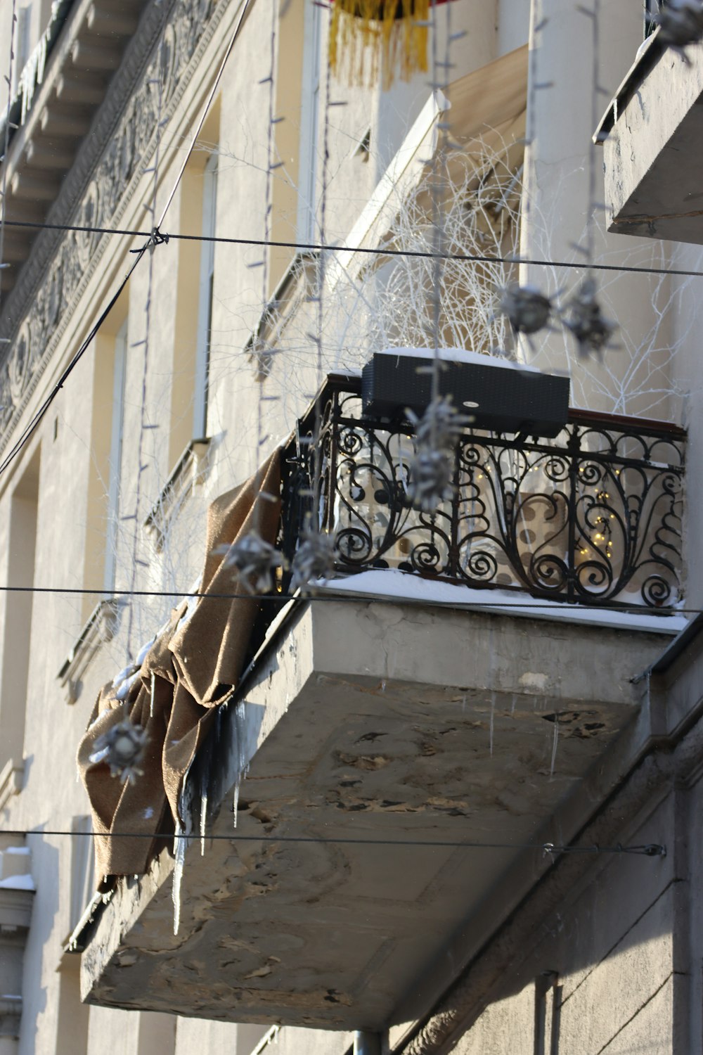 un balcon d’un immeuble auquel est suspendu un lustre