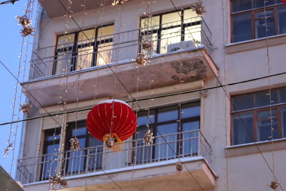 a red lantern hanging from a wire in front of a building