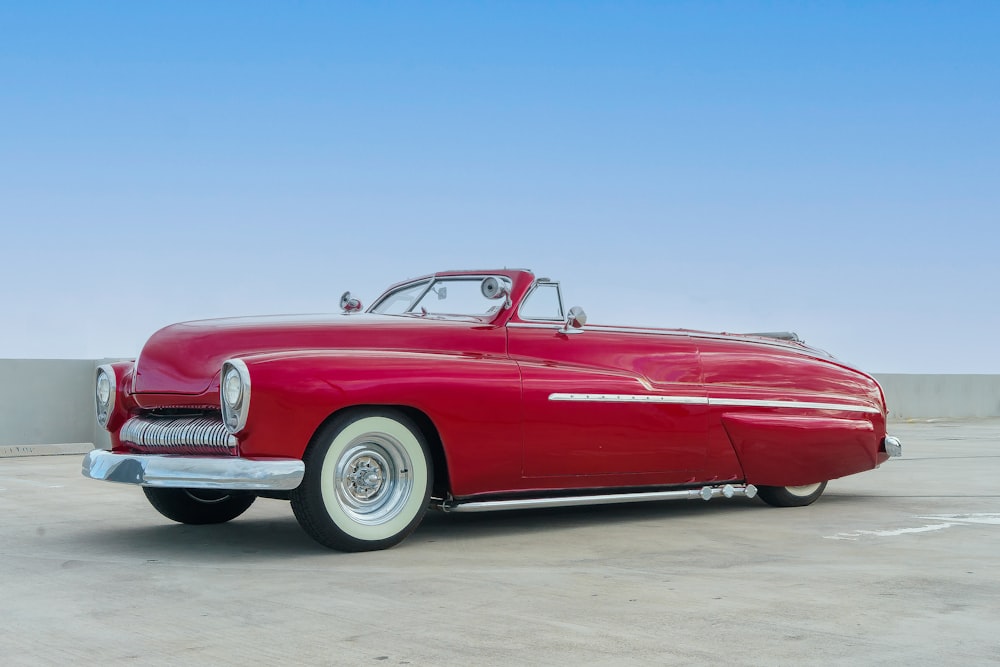 a red classic car parked in a parking lot